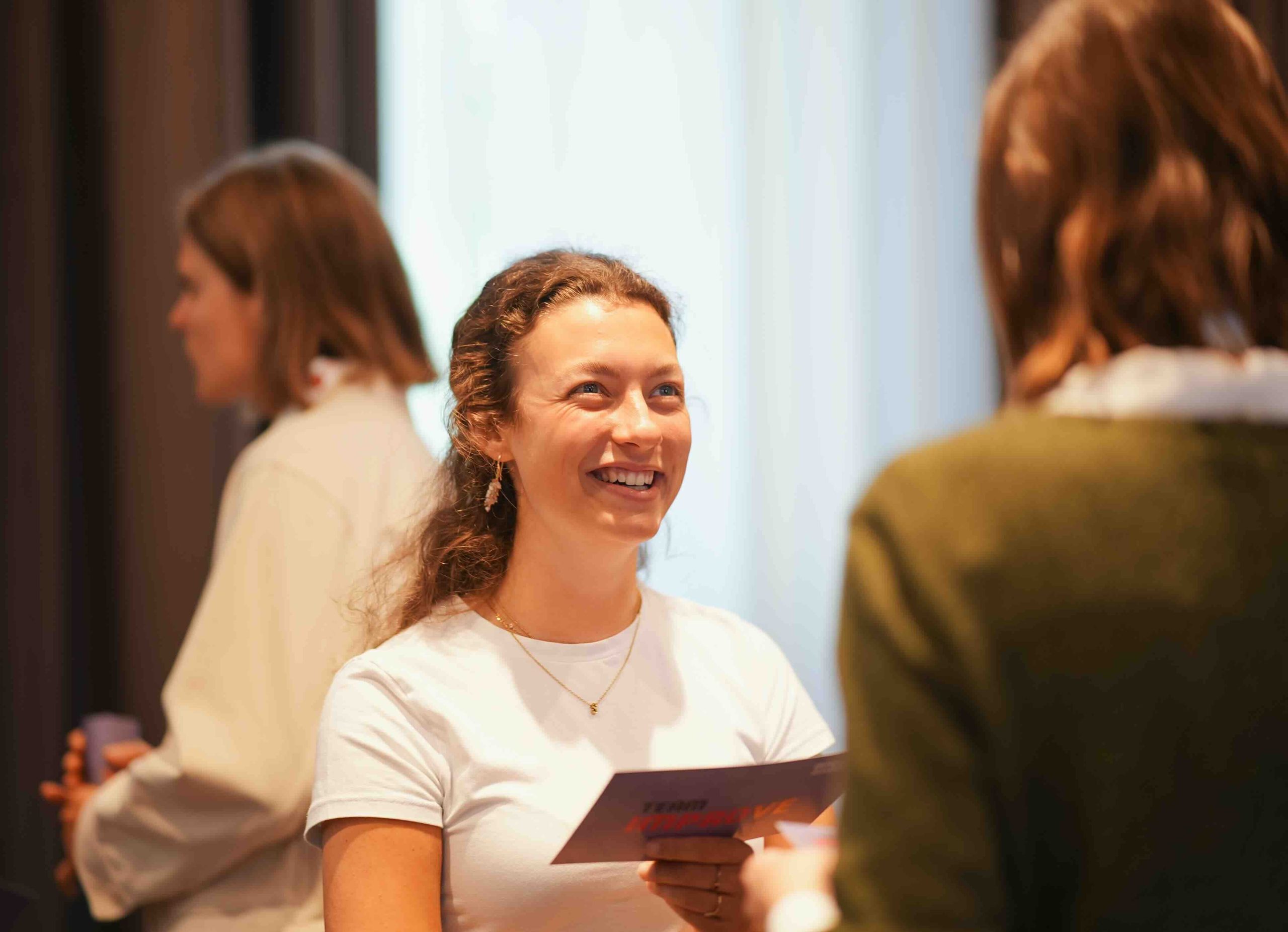 Team IMPROve: lachende Teilnehmerin im Austausch bei einem Teamevent